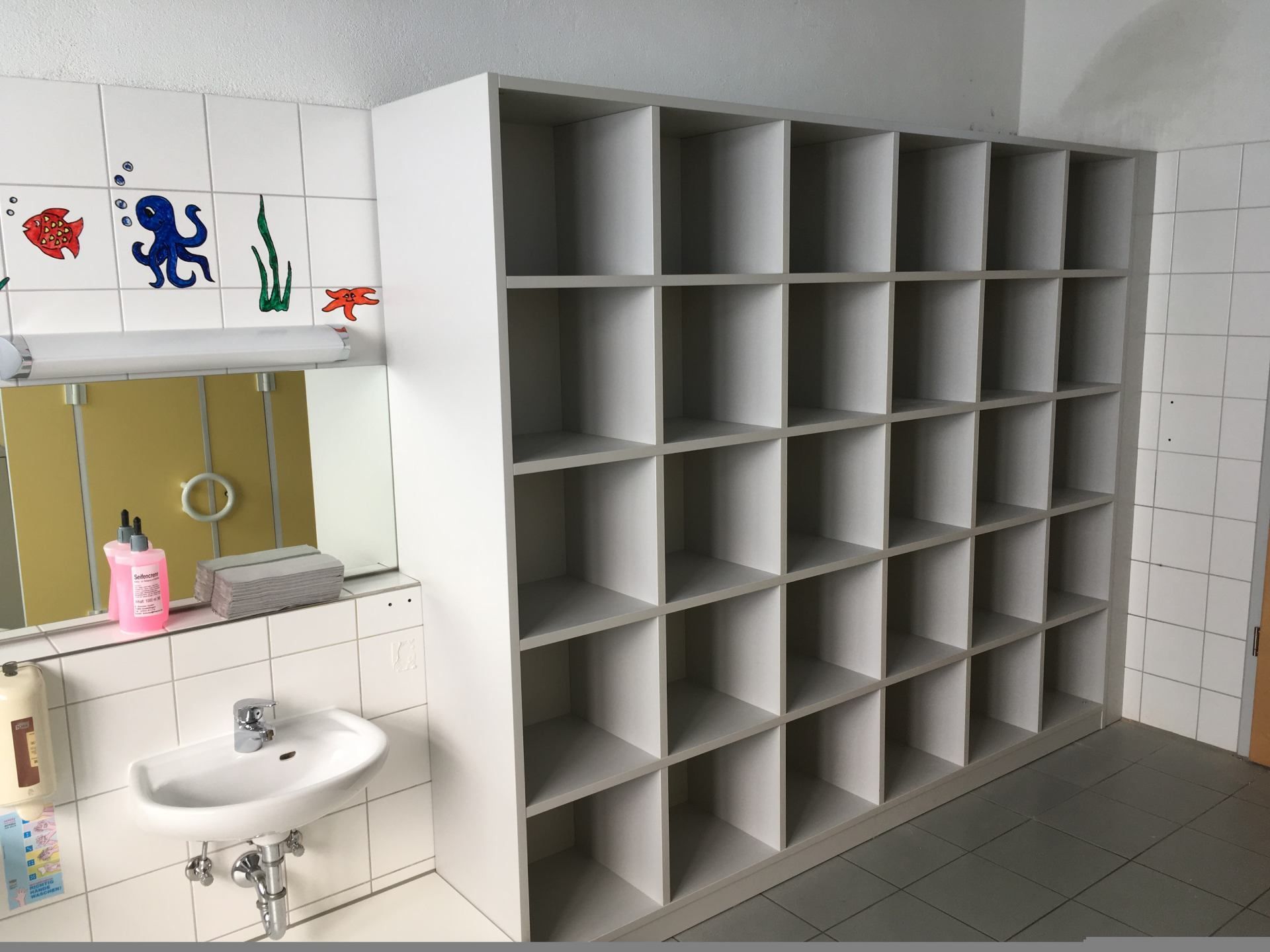 Ein Badezimmer mit Waschbecken, Regalen und Spiegel.