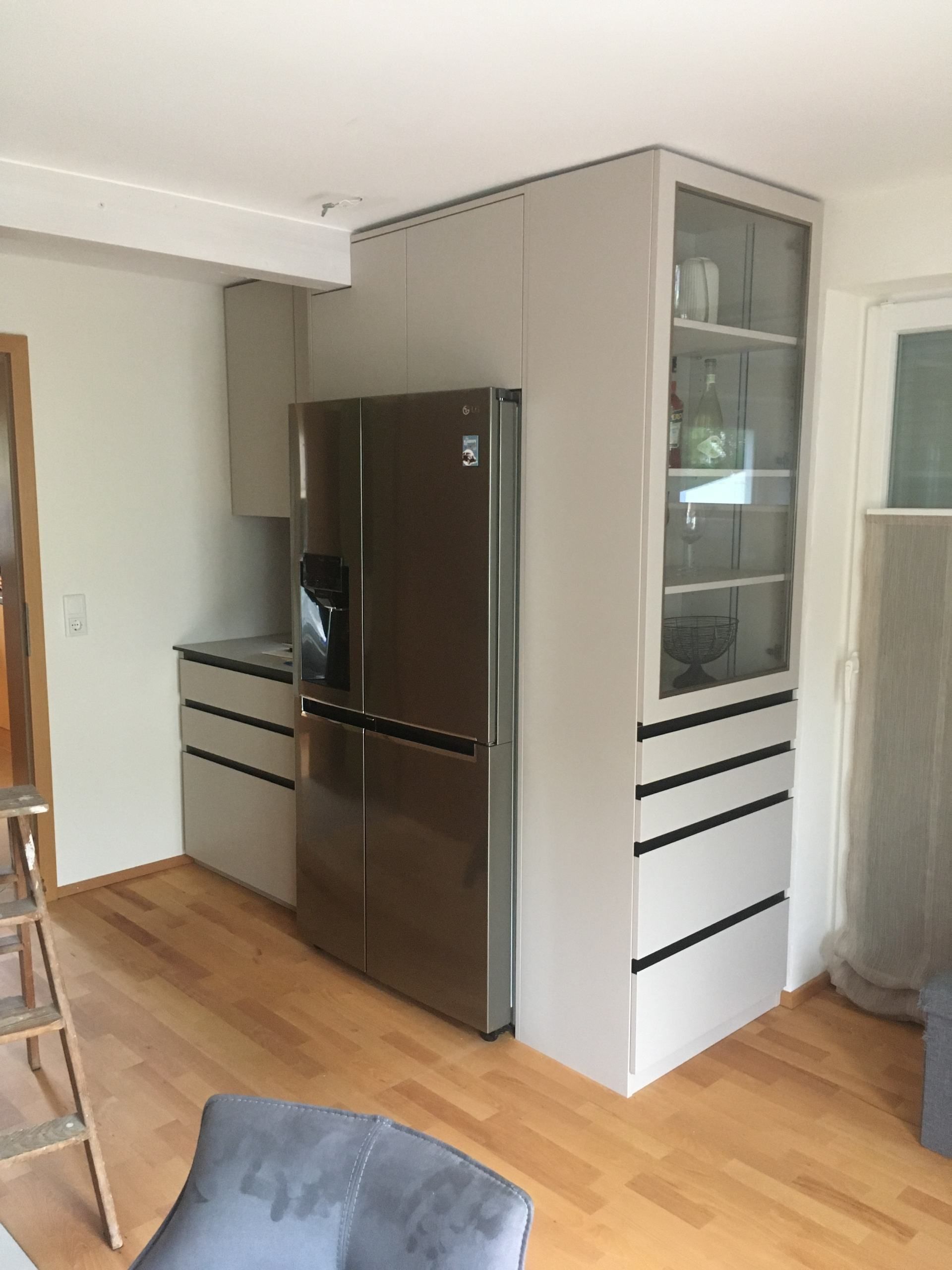 Ein Wohnzimmer mit einem Edelstahlkühlschrank und Schränken.