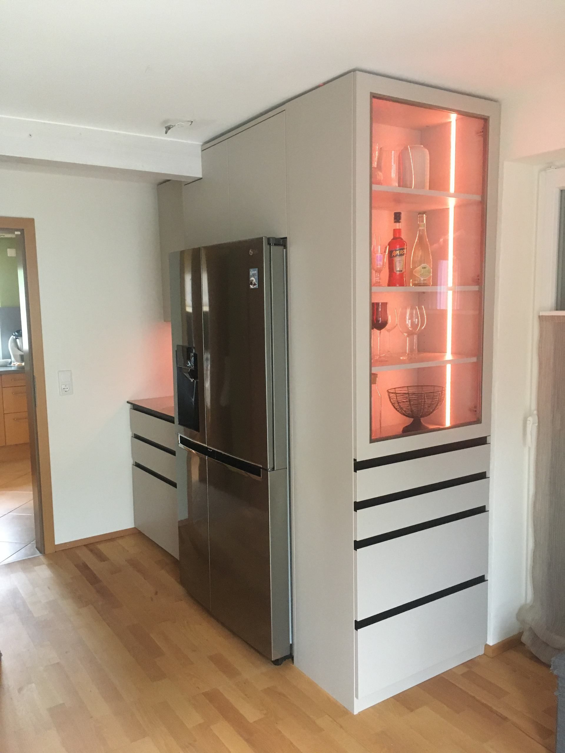 Eine Küche mit Edelstahlkühlschrank und Glasvitrine.