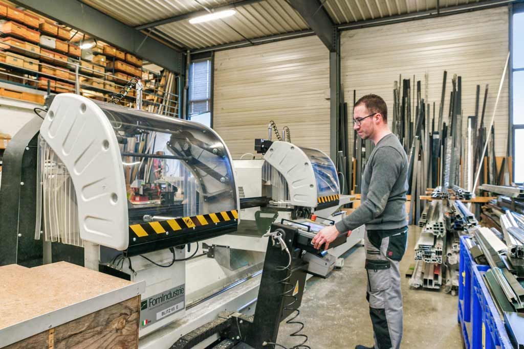 Un homme manipule des machines dans un atelier, entouré de matériaux et d'équipements.