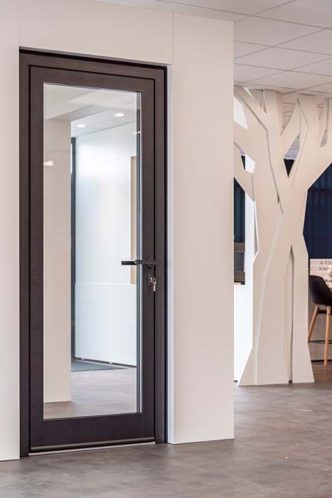 Échantillons de verre texturé dans un support en bois, contre un mur de lattes de bois horizontales.