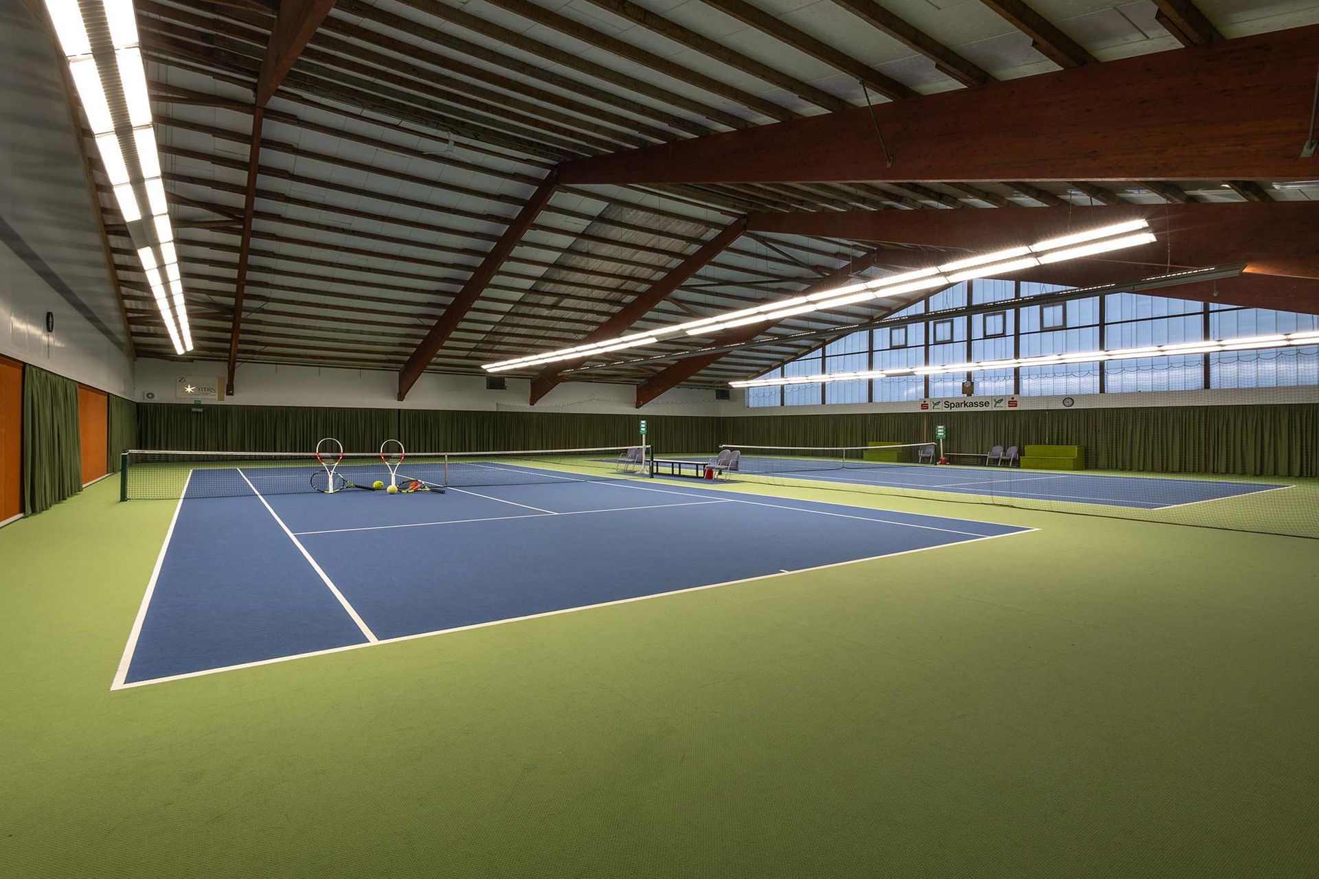 Eine Tennishalle mit einem blauen und einem grünen Platz