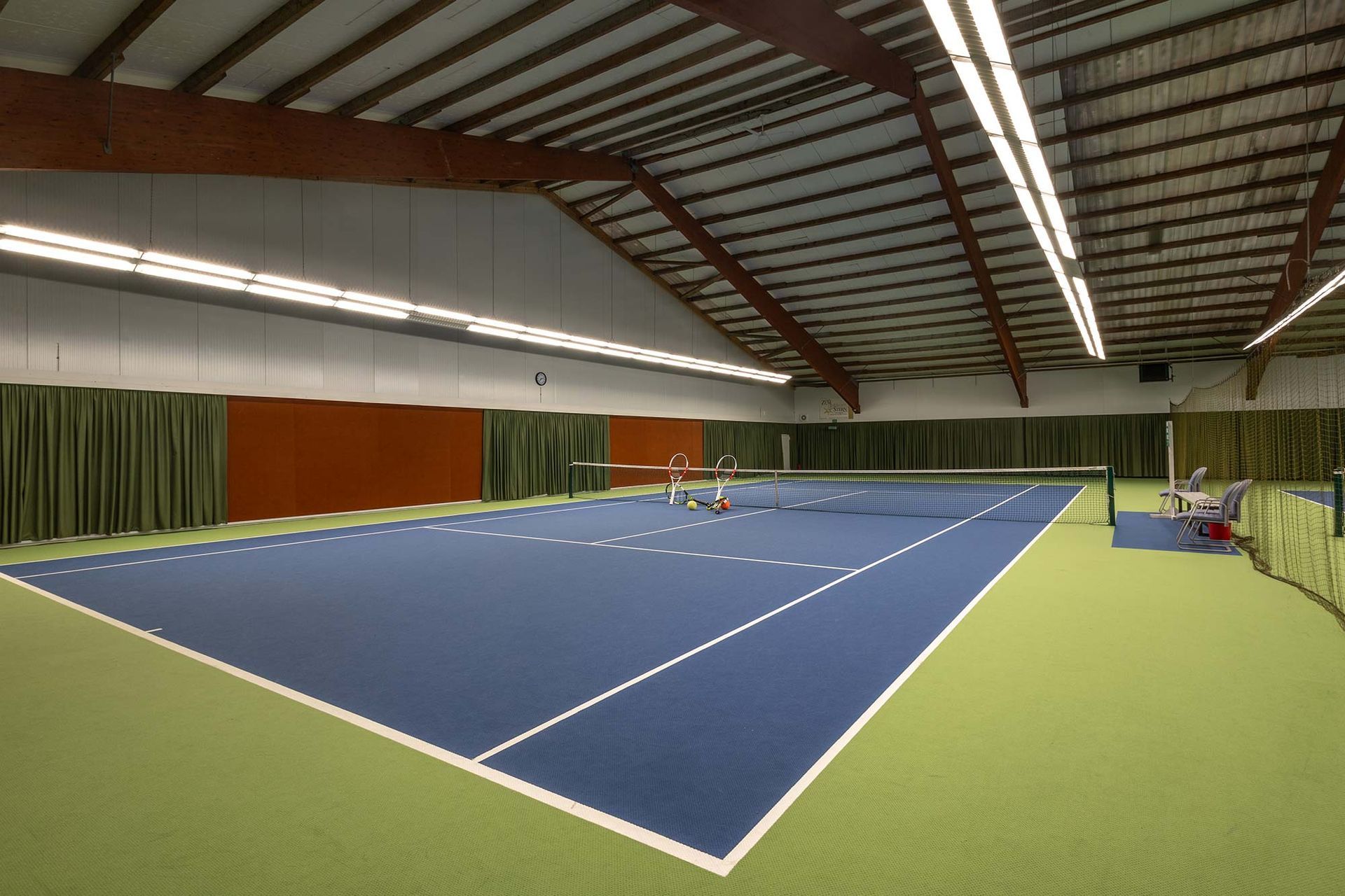 Zwei Personen spielen Tennis in einer Tennishalle.