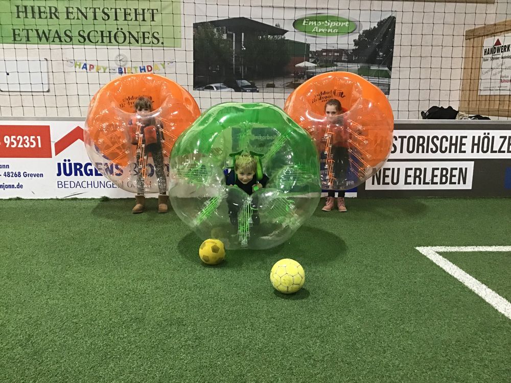 Eine Gruppe Kinder spielt Bubble-Fußball auf einem Feld.
