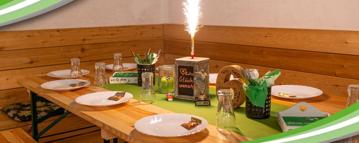 Ein Tisch mit Tellern, Gläsern und einer Wunderkerze darauf.