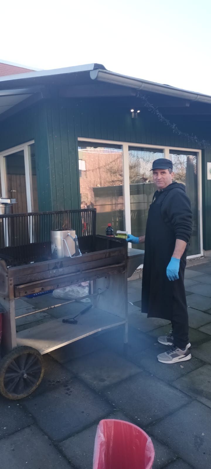 Ein Mann steht vor einem Grill, aus dem Rauch aufsteigt.