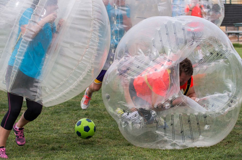Eine Gruppe Kinder spielt Bubble-Fußball auf einem üppigen grünen Feld.