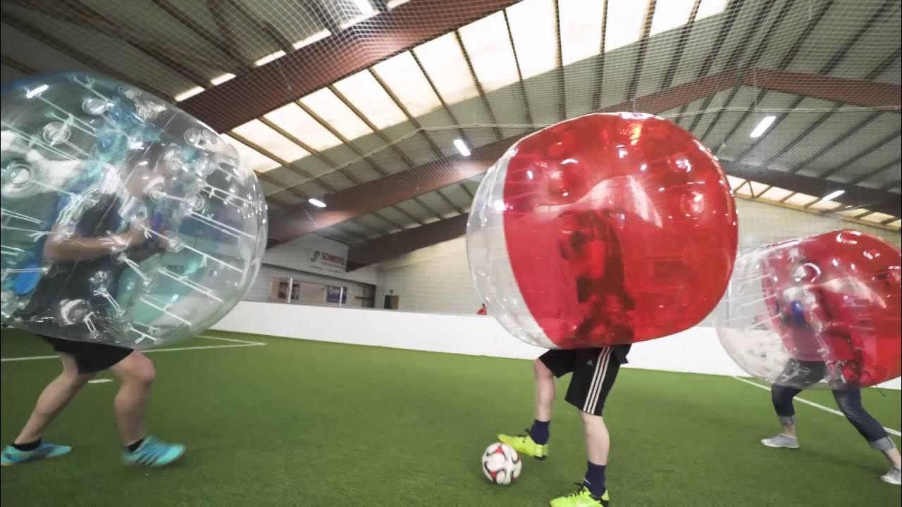 Eine Gruppe von Leuten spielt Bubble-Fußball in einer Indoor-Arena.