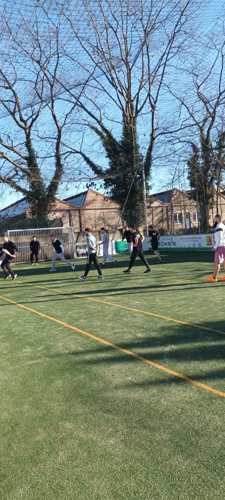 Eine Gruppe von Leuten spielt auf einem Feld Fußball.