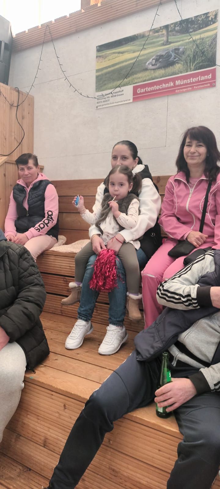 Eine Gruppe von Leuten sitzt auf einer Holzbank.