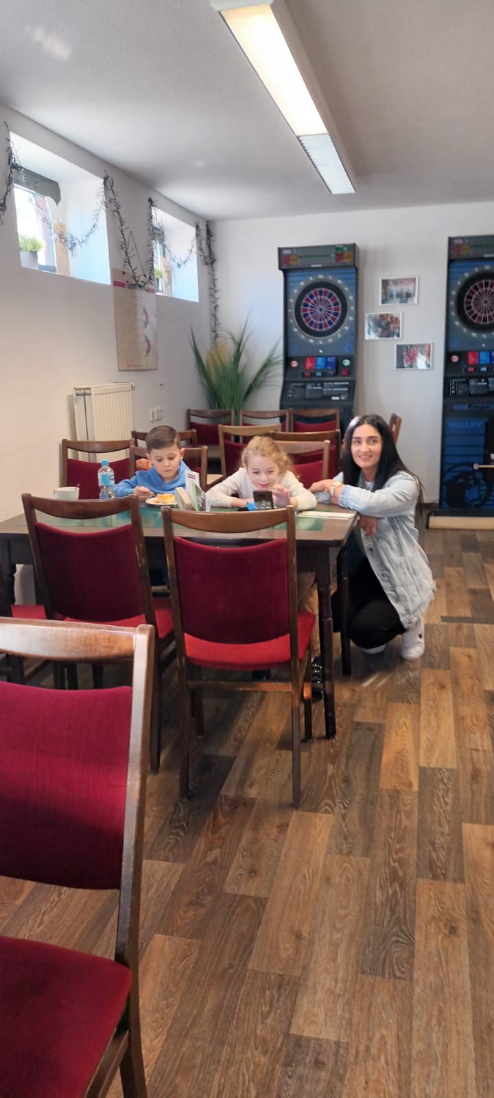 Eine Frau und zwei Kinder sitzen an Tischen in einem Restaurant.