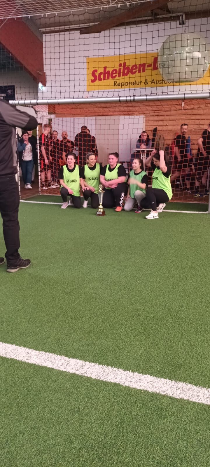 Eine Gruppe von Leuten sitzt auf einem Fußballfeld und hält einen Pokal in den Händen.