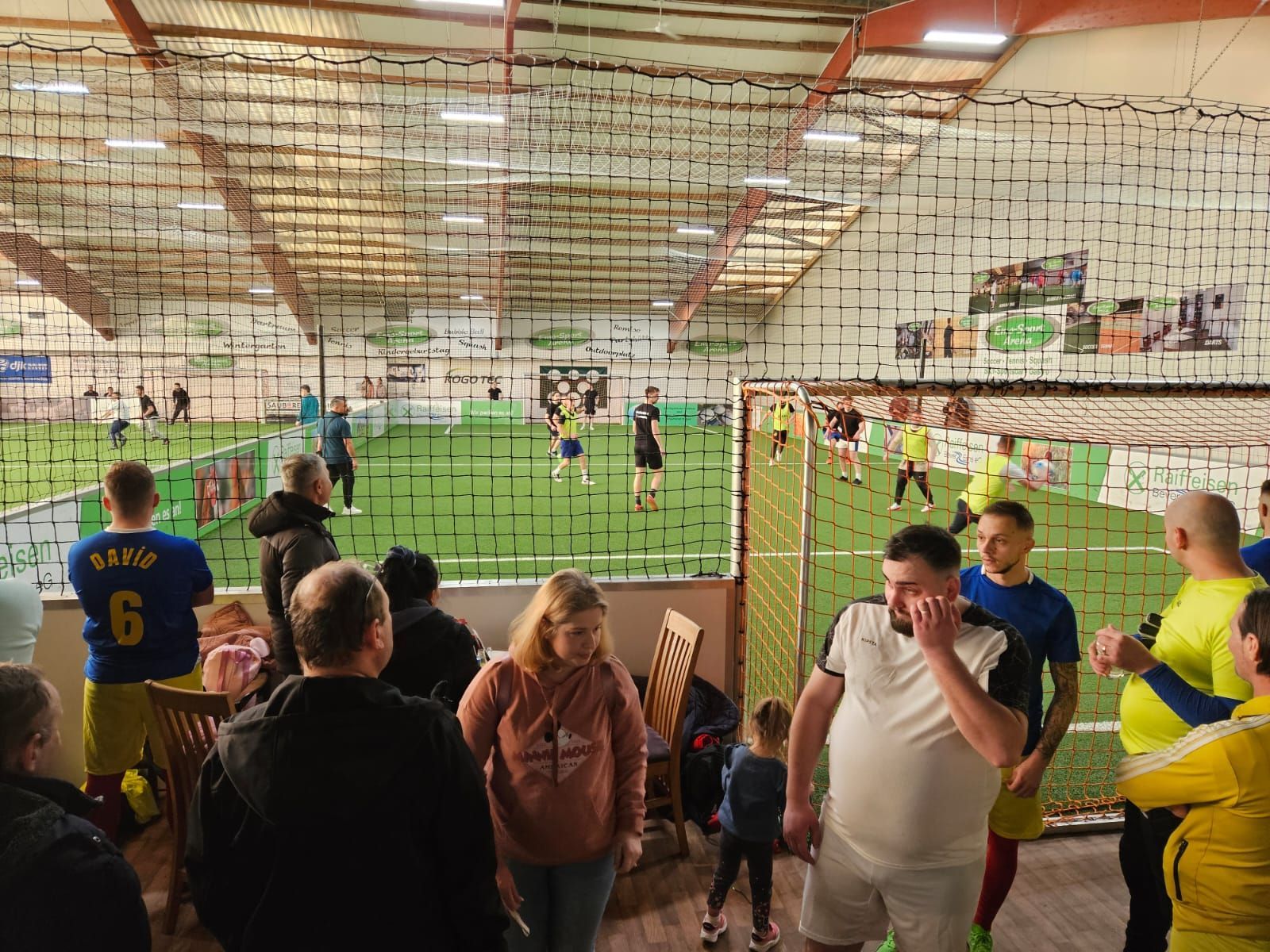Eine Gruppe von Leuten sieht sich in einem Hallenstadion ein Fußballspiel an.