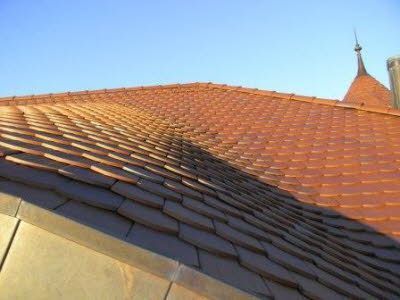 Eine Nahaufnahme eines roten Ziegeldachs mit einem blauen Himmel im Hintergrund.