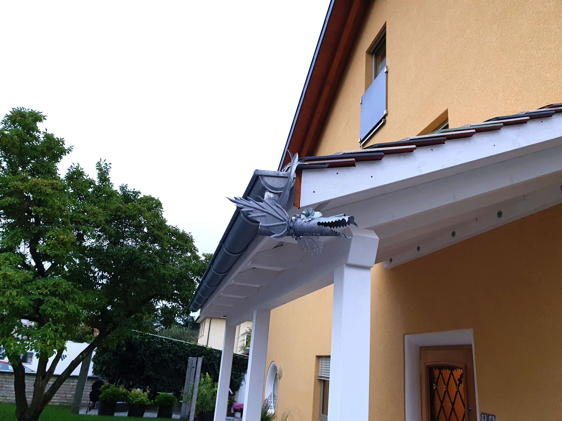 ein gelbes Haus mit einer weißen Veranda und einer Fledermausstatue auf dem Dach