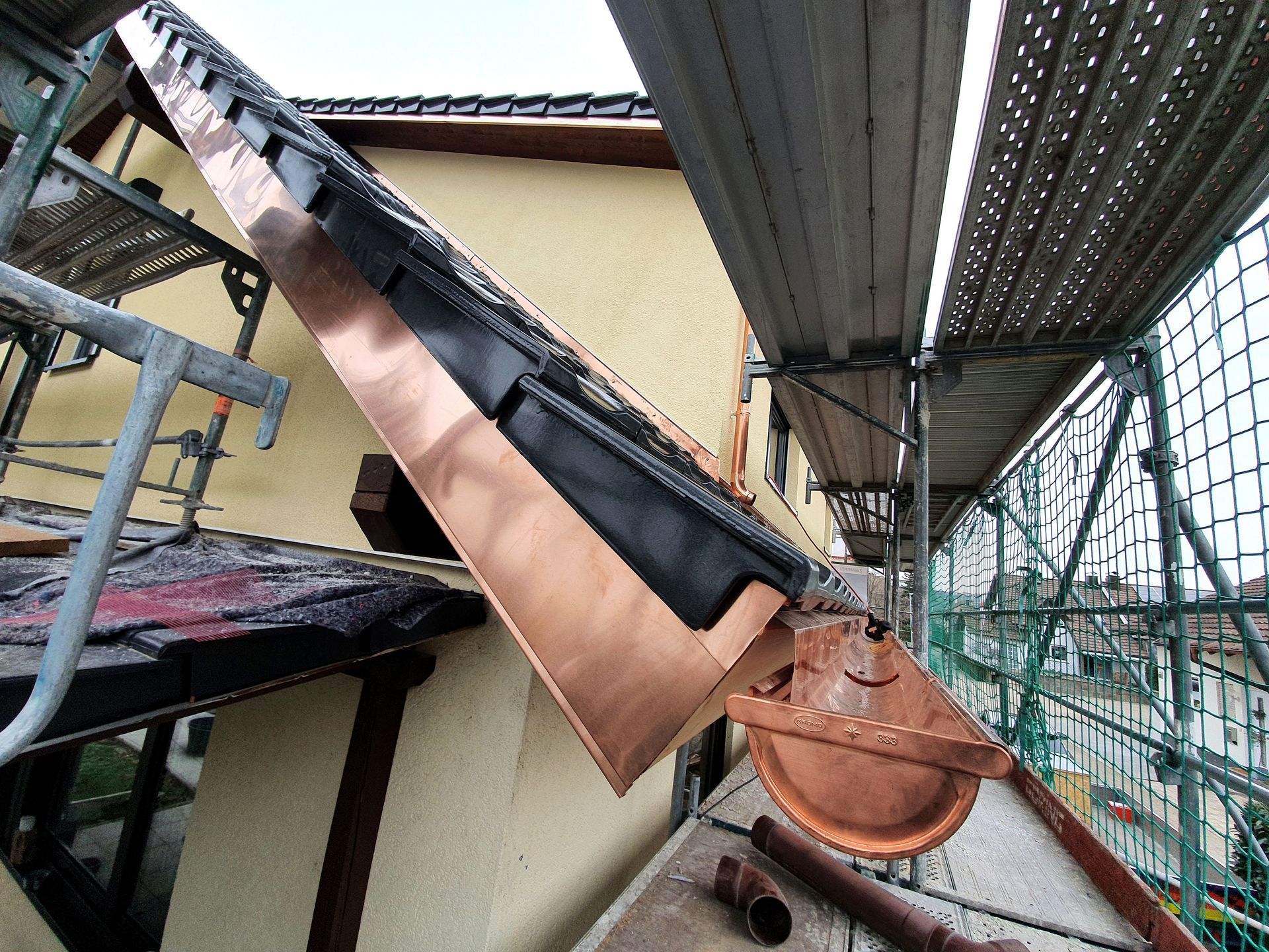 An der Seite eines Gebäudes wird eine Kupferrinne installiert