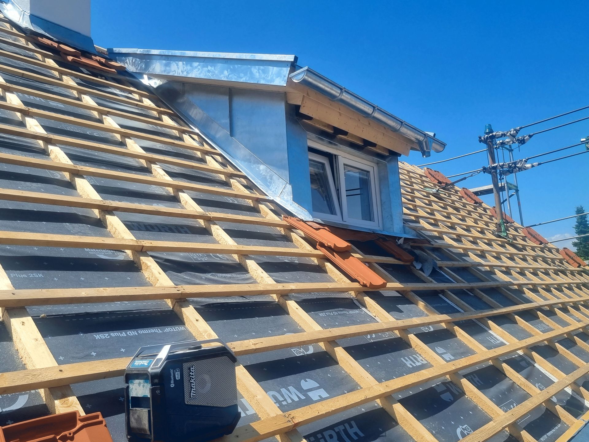 Es wird ein Dach mit Holzbalken und Ziegeln gebaut.