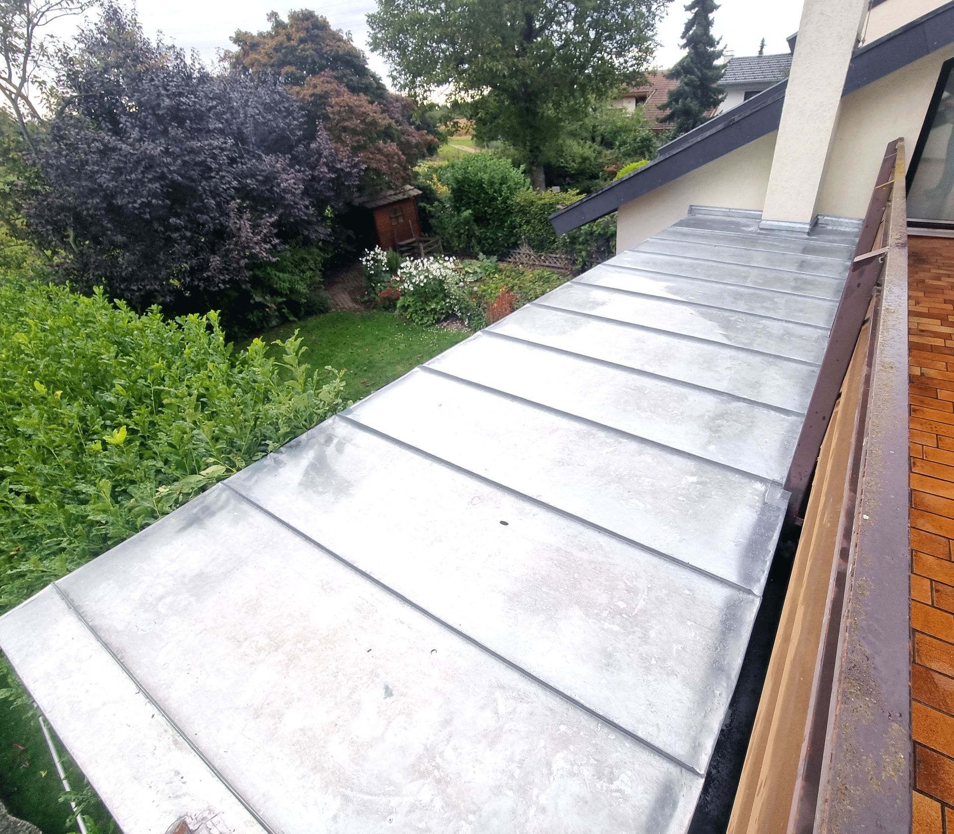 ein Balkon mit Dach und ein Garten im Hintergrund