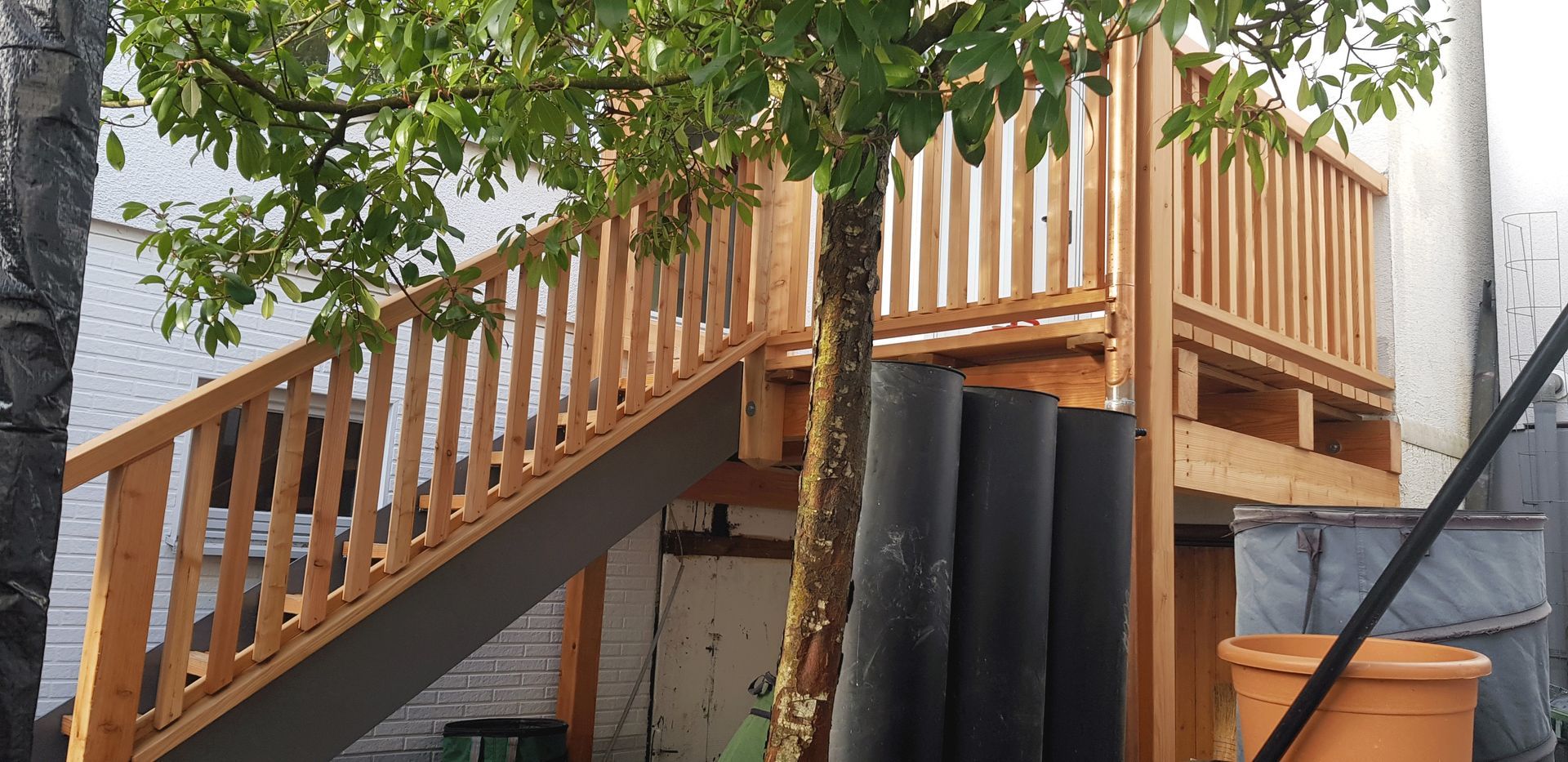 Ein Holzdeck mit Treppen, die hinaufführen, und einem Baum im Hintergrund.