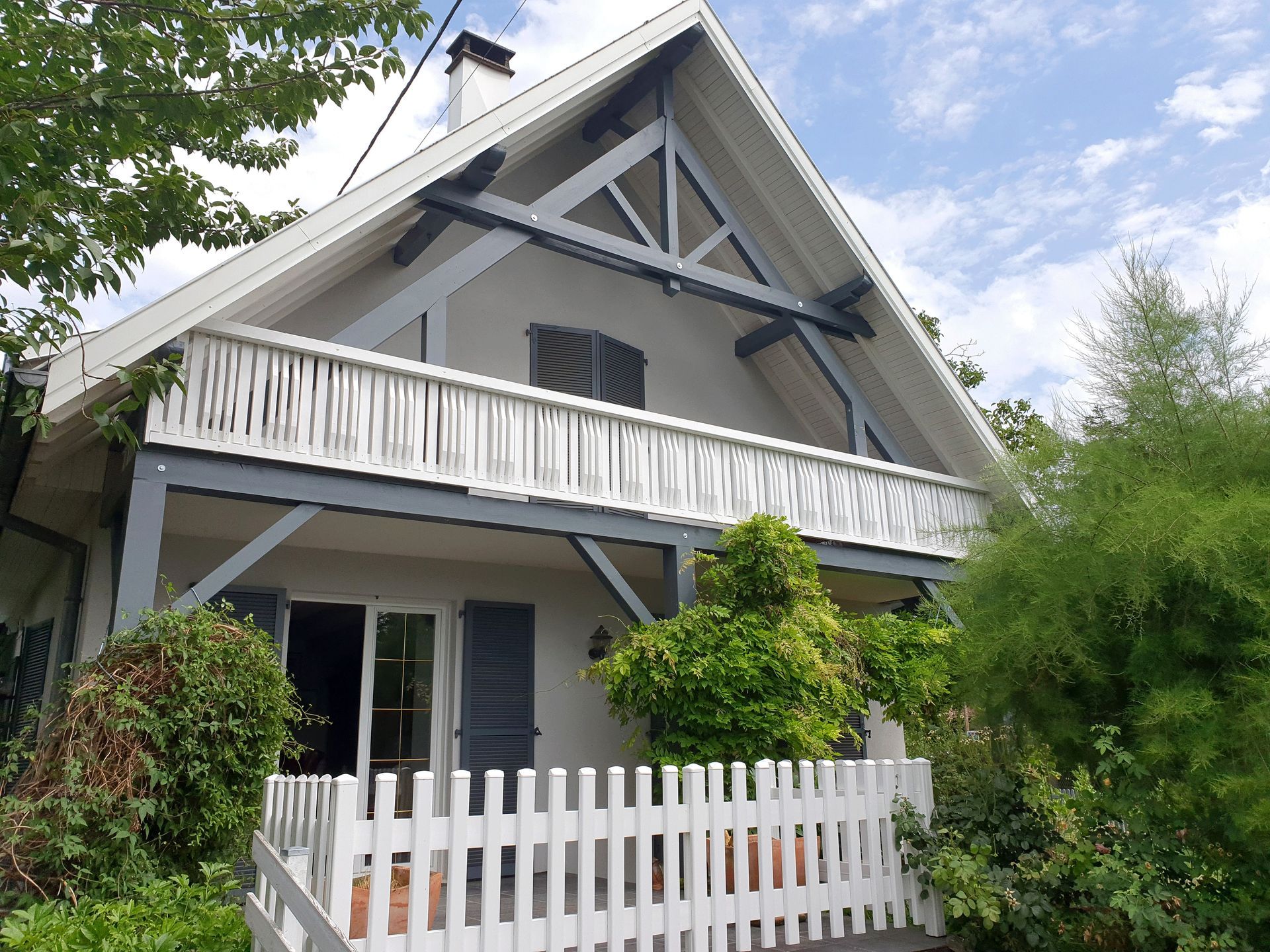 Ein weißes Haus mit Balkon und weißem Lattenzaun