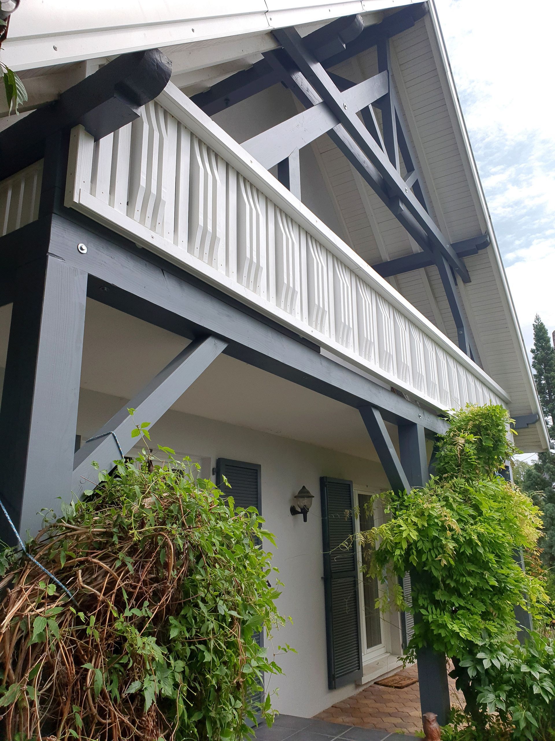 Die Vorderseite eines Hauses mit Balkon und Dach.