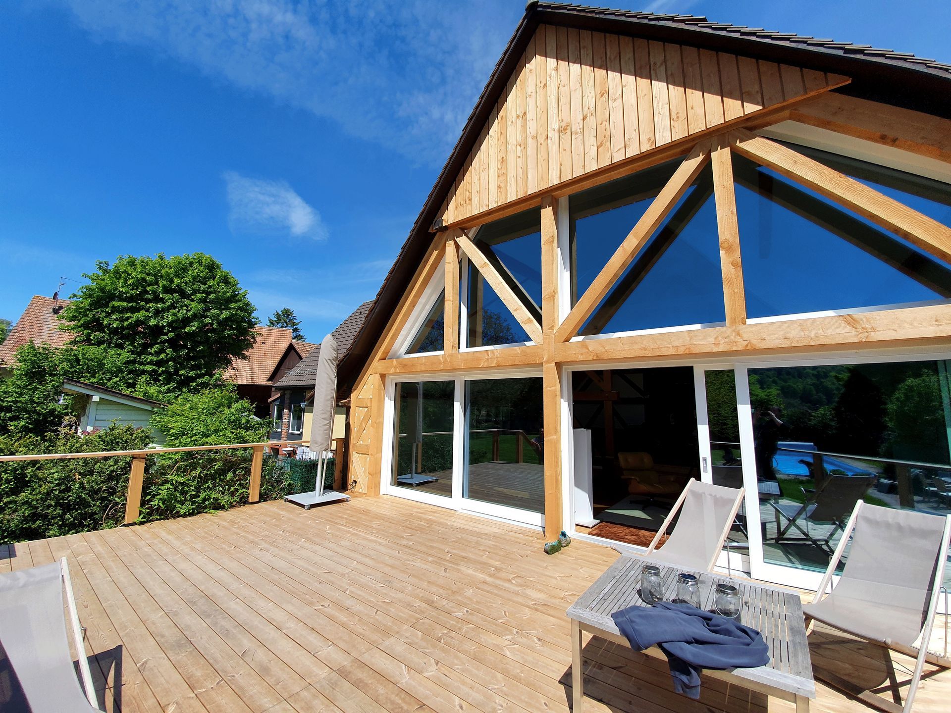 Ein großes Haus mit einer Holzterrasse und Stühlen davor