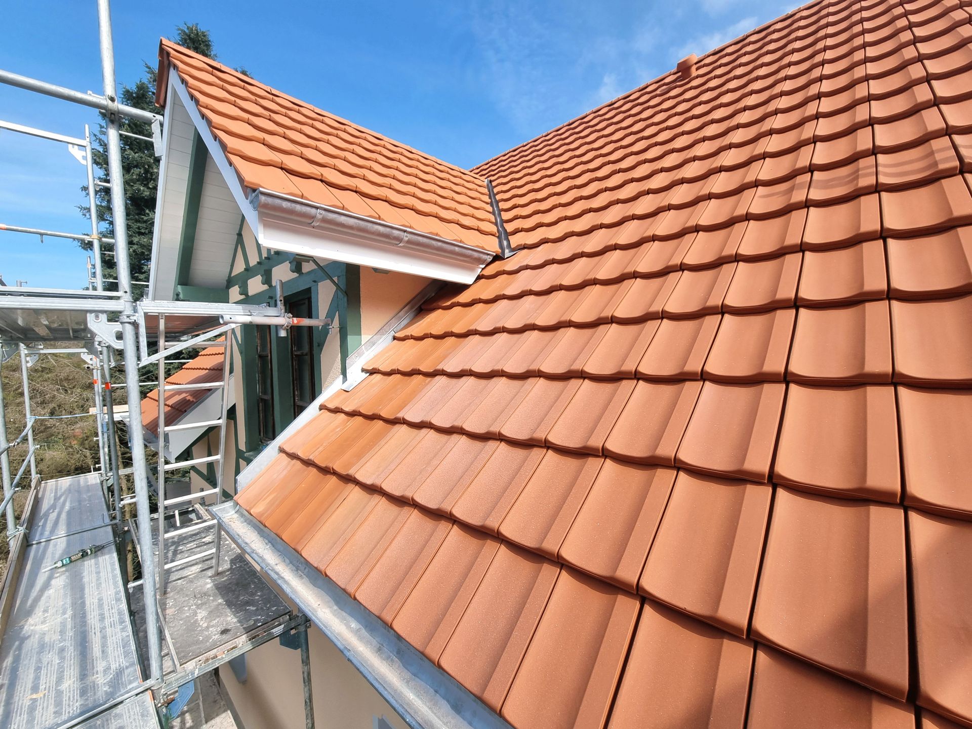 Auf einem Haus wird ein rotes Ziegeldach installiert