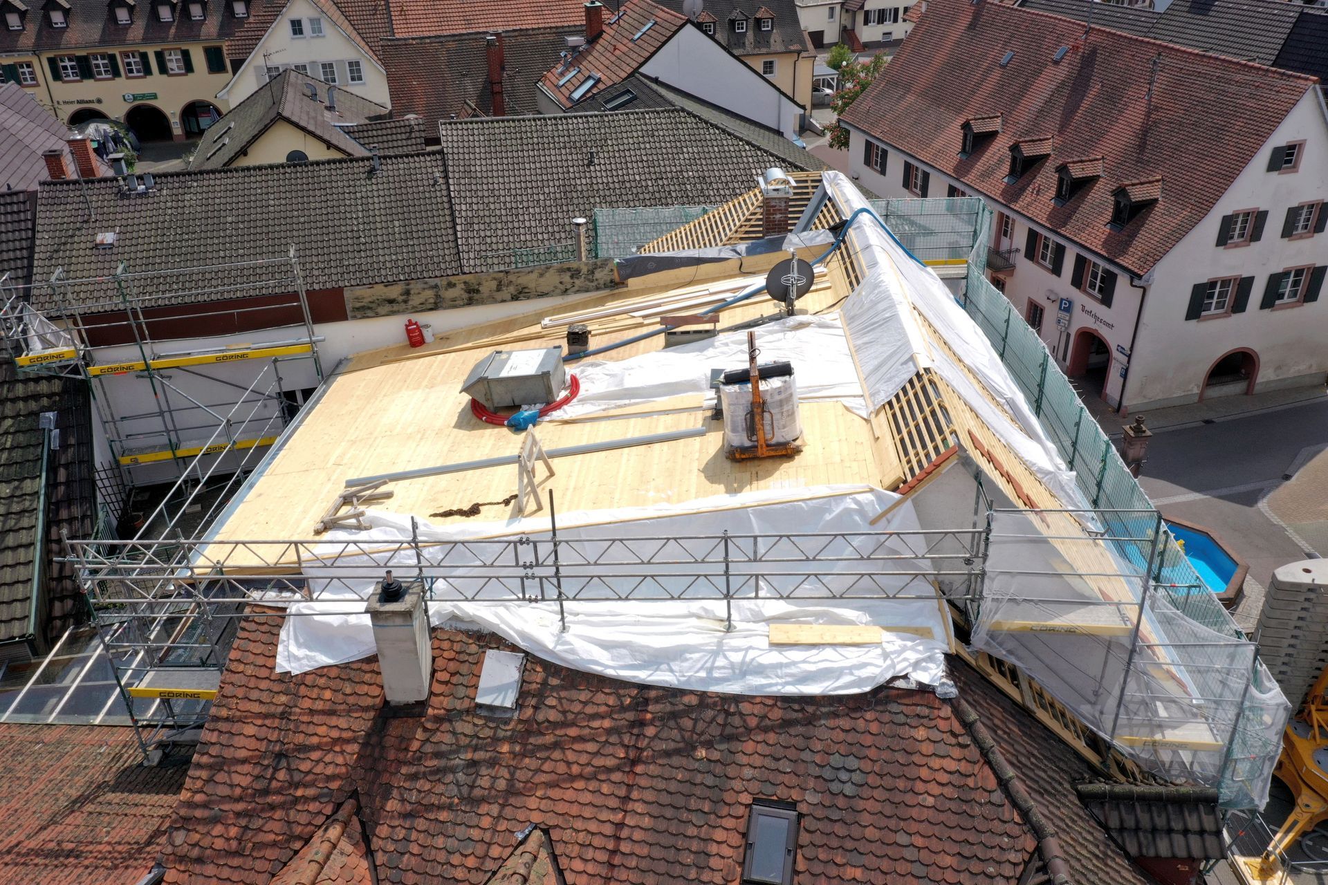 Eine Luftaufnahme eines Daches mit Gerüst und einer Plane darauf.
