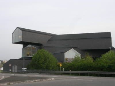 ein großes schwarzes Gebäude mit vielen Fenstern und Bäumen davor