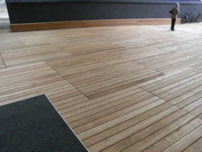 eine Person, die auf einem Holzboden neben einer schwarzen Wand steht