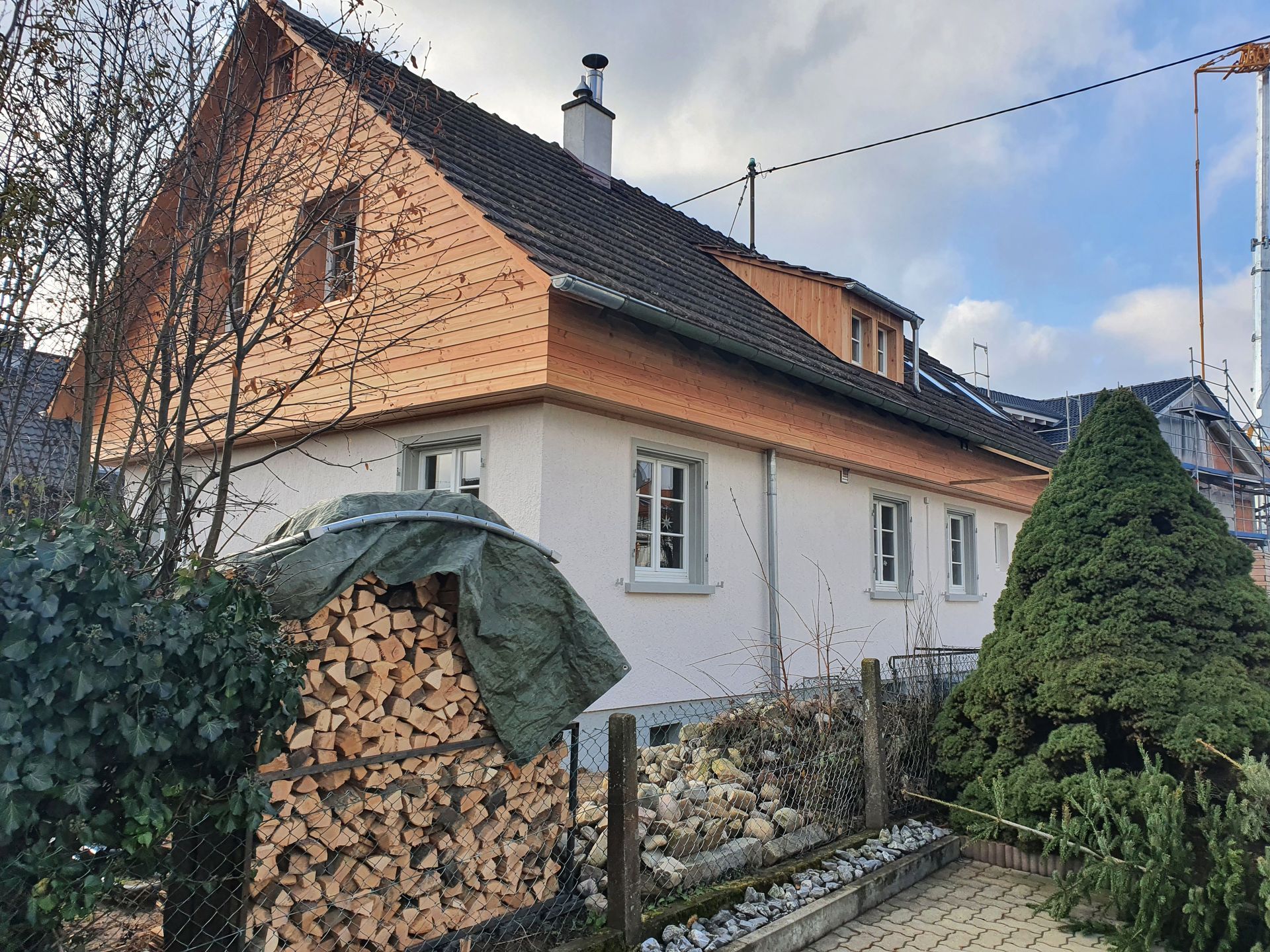 Vor einem Haus liegt ein Stapel Holz.