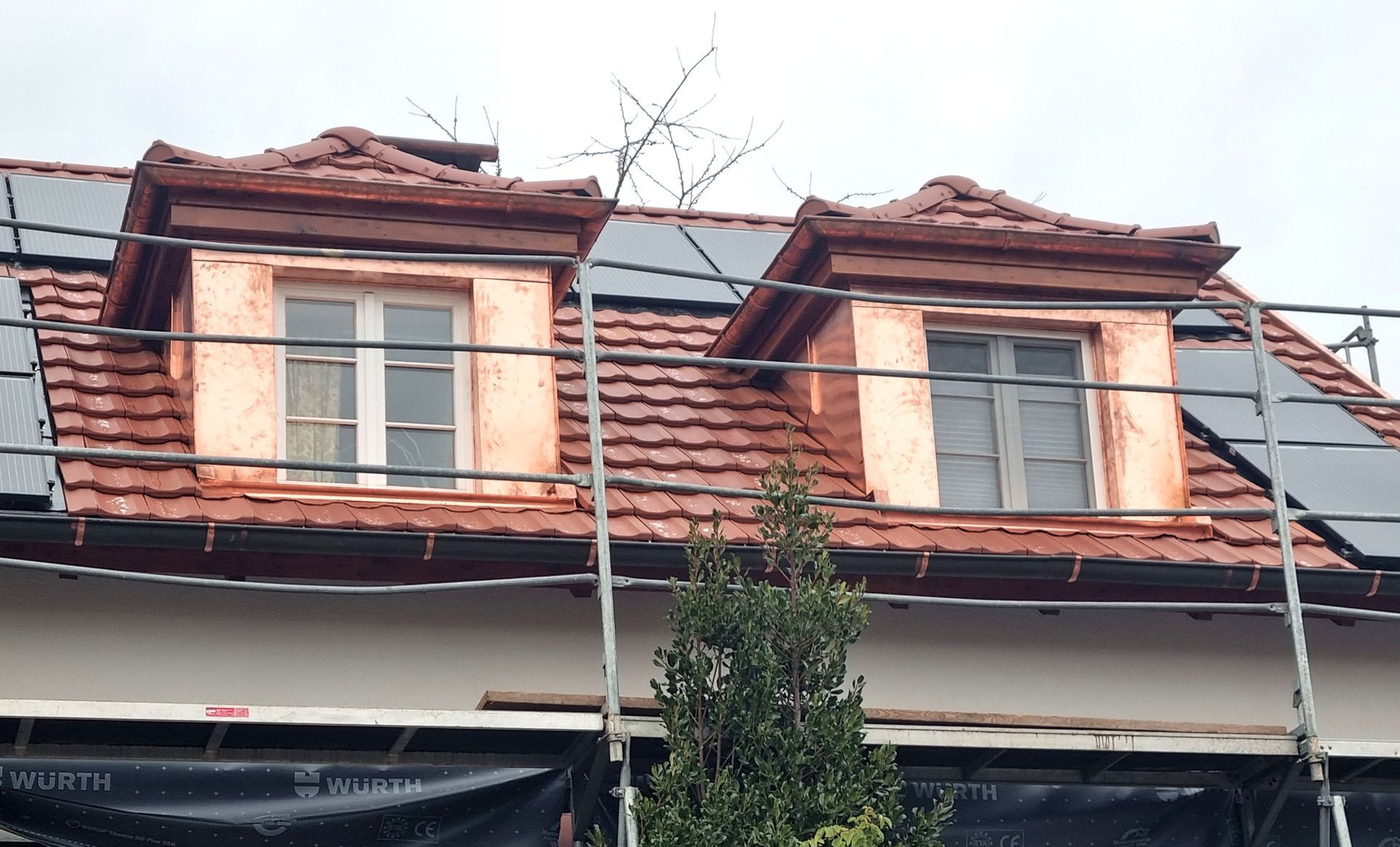 ein Dach mit zwei Fenstern und Sonnenkollektoren darauf