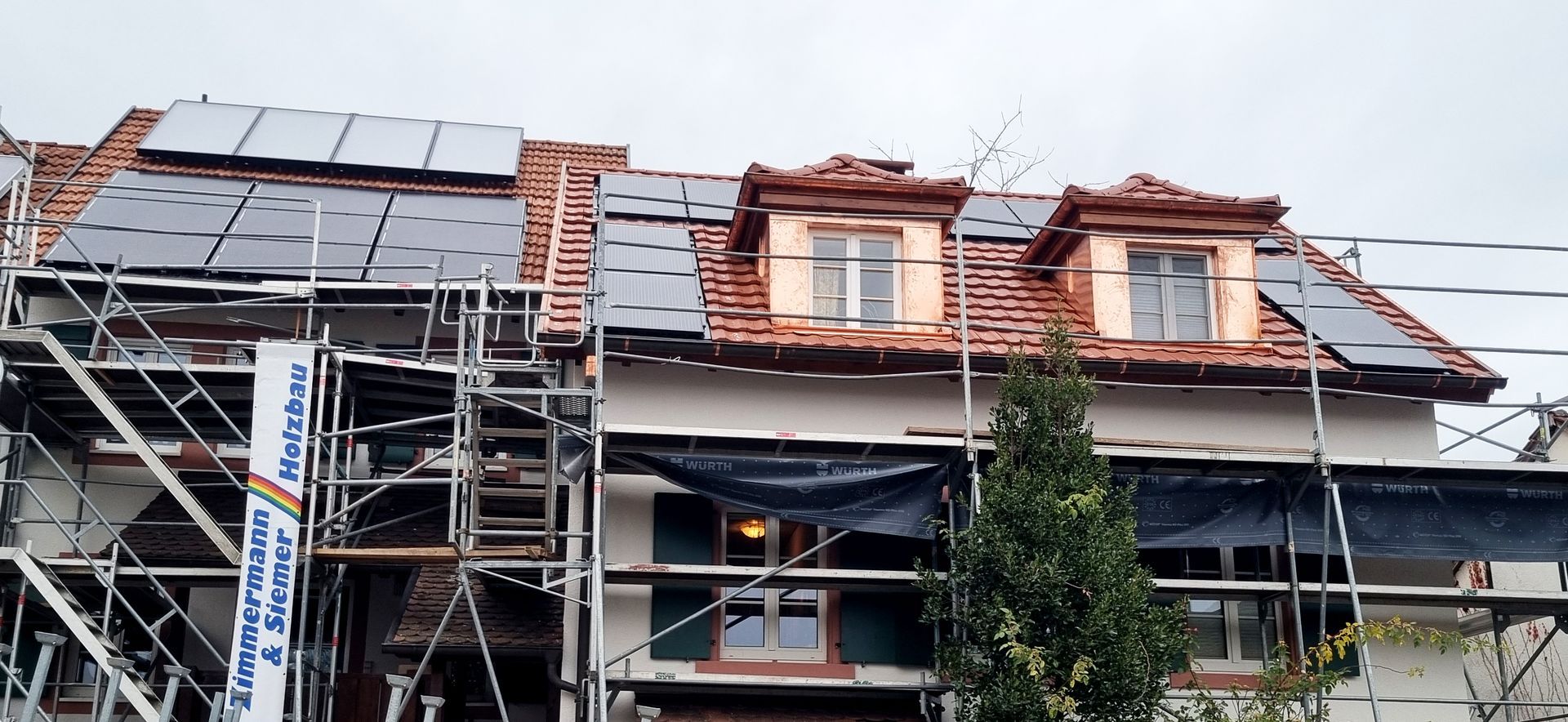 ein Haus mit Gerüst und Sonnenkollektoren auf dem Dach