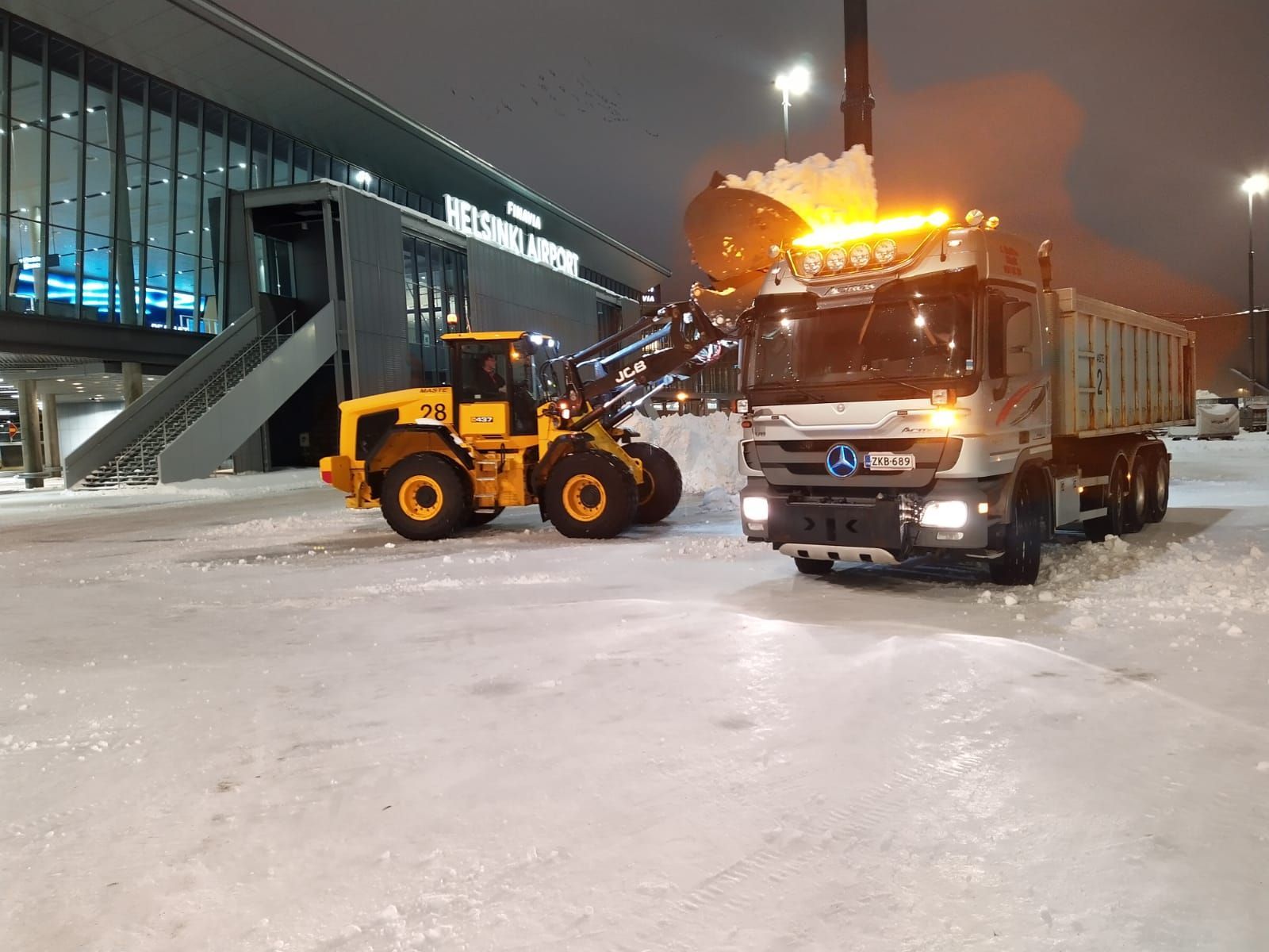 Luminen lentokentän asemataso, jossa lastaaja kuorma-auton vieressä lastaamassa jäänpoistonestettä yöllä