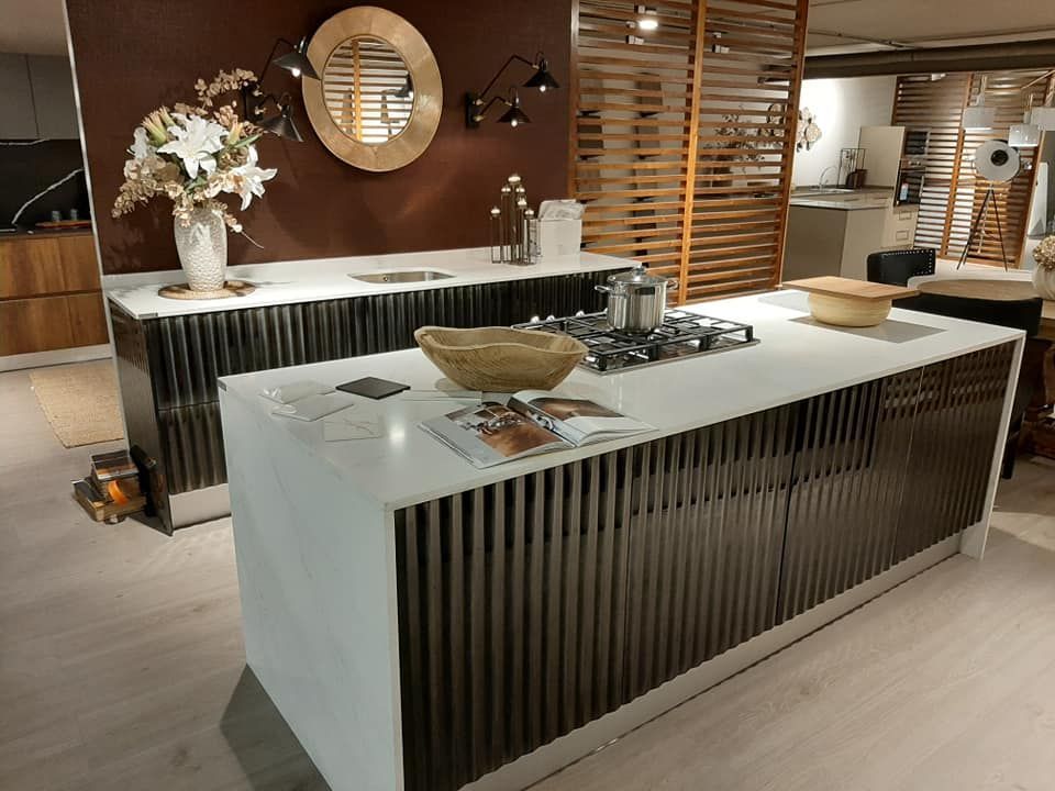 Cocina moderna con encimeras blancas y gabinetes de listones oscuros.