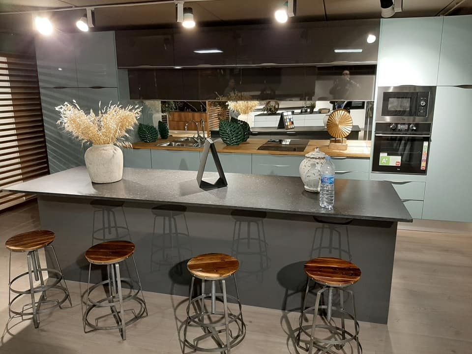 Cocina moderna con isla, encimera gris, gabinetes azules, taburetes de madera.