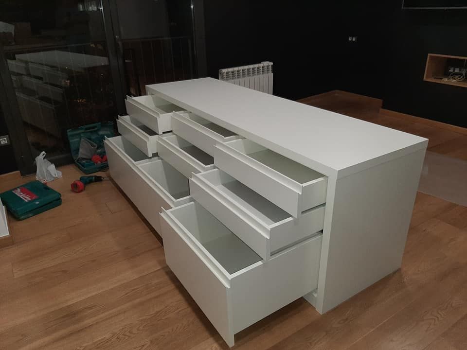 Cómoda blanca con múltiples cajones abiertos sobre un piso de madera.