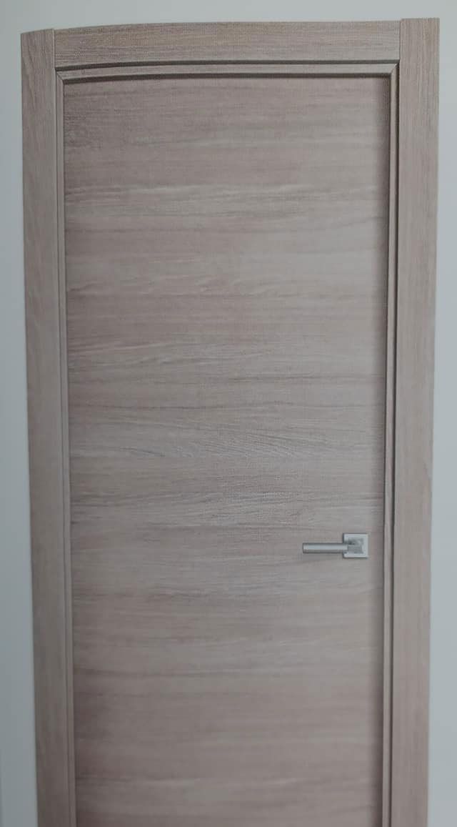 Una puerta de madera cerrada, de color claro, con tirador plateado.