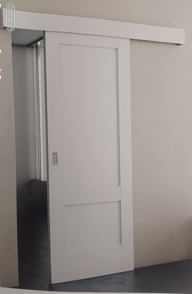 Puerta corrediza blanca sobre riel contra pared neutra.