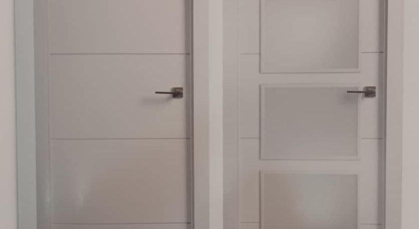 Dos puertas interiores blancas; una sólida y otra con tres paneles de vidrio esmerilado.