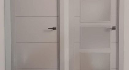 Dos puertas interiores blancas; una sólida y otra con tres paneles de vidrio esmerilado.