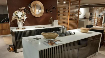 Isla de cocina con encimera blanca, gabinetes de madera oscura, estufa y un cuenco decorativo.