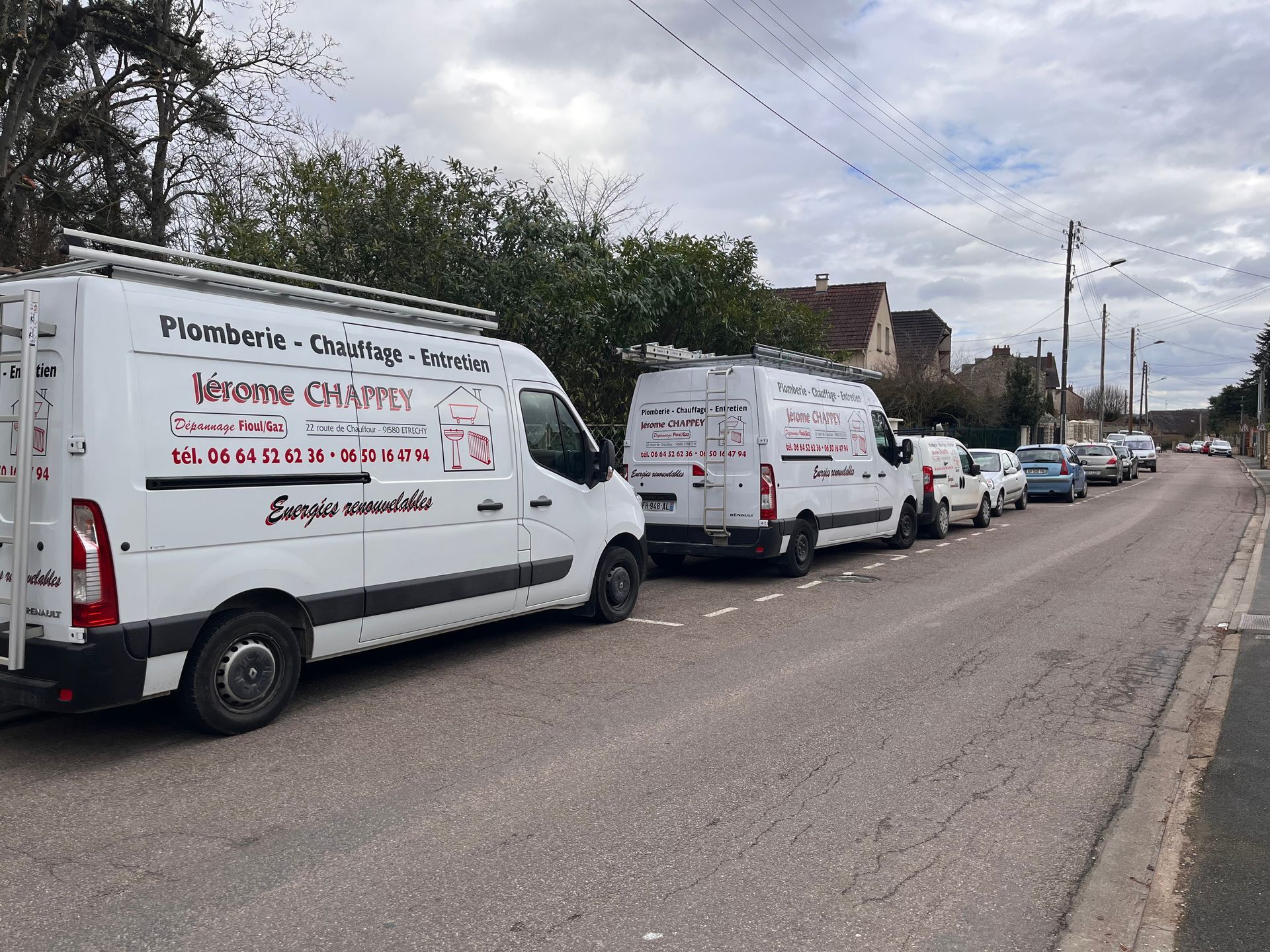 Les camions de l'entreprise de plomberie et de chauffage stationnés devant le chantier
