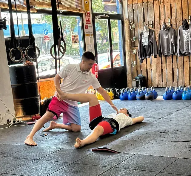 Un hombre está estirando la pierna de una mujer en un gimnasio.