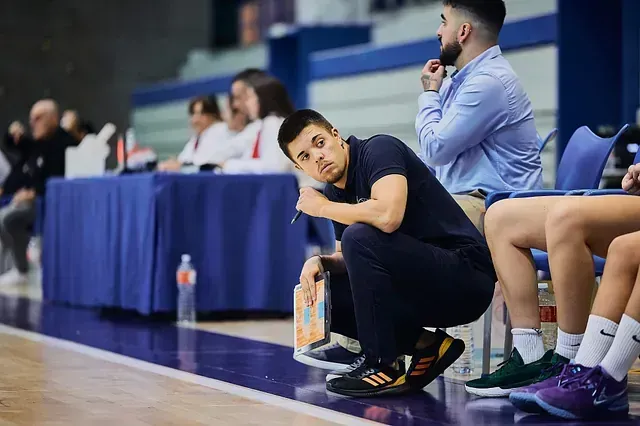 Un hombre está sentado al margen de un partido de baloncesto.