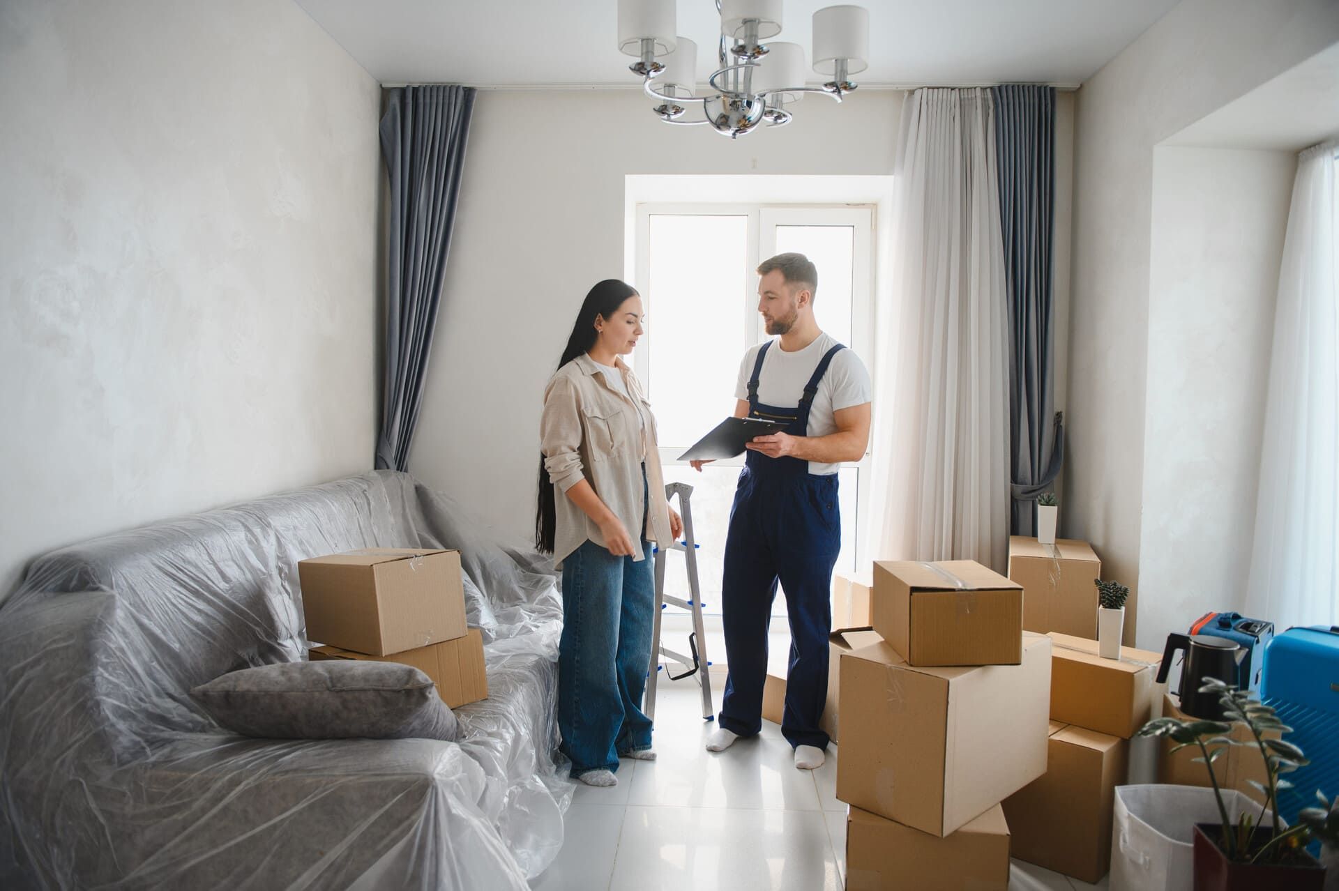 Una mujer habla con un trabajador uniformado rodeado de cajas de mudanza en una habitación.