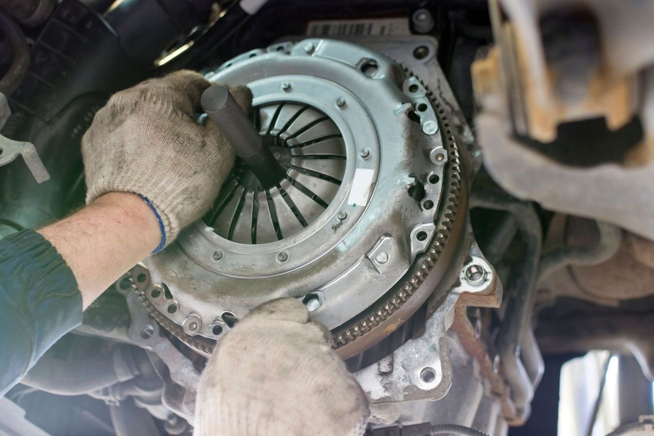 Des mains gantées installent un embrayage automobile à l’intérieur d’un carter de transmission