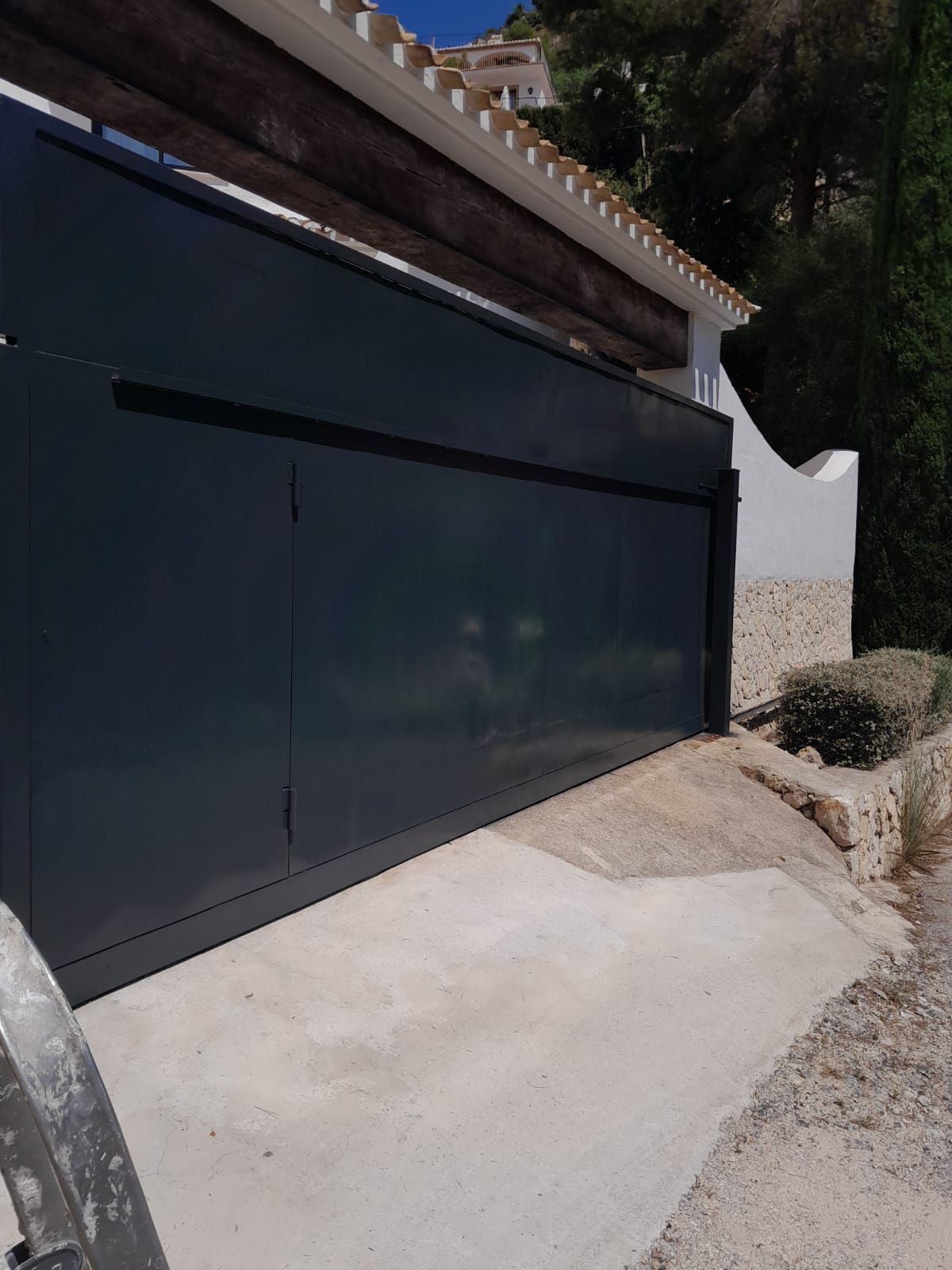 Una puerta corrediza negra está situada delante de una casa.