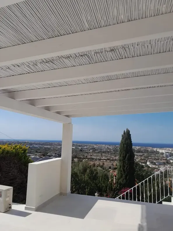 Una pérgola blanca con vista a una ciudad y al océano.