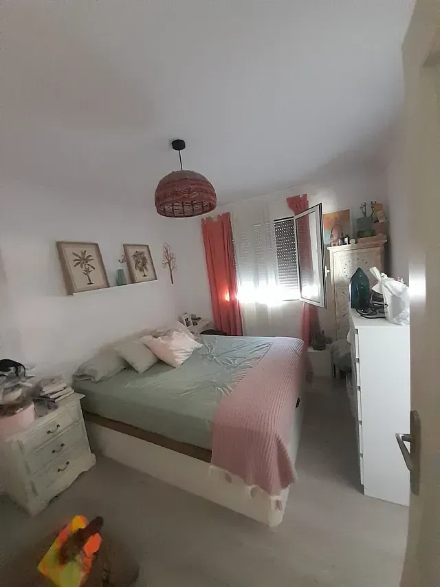 Un dormitorio con cama, mesita de noche, cómoda y ventana.